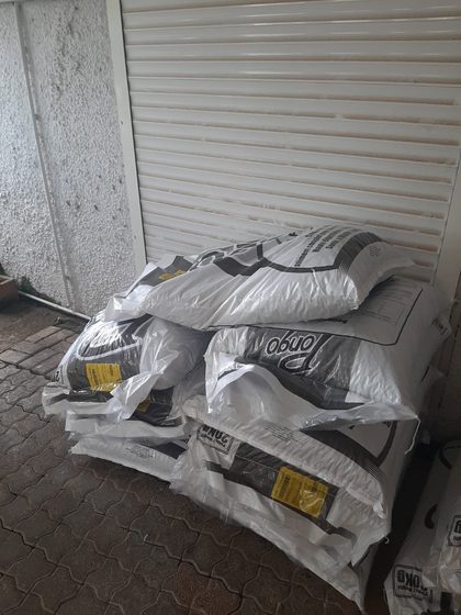 Stacked bags of animal feed on a pallet outside a shuttered storefront